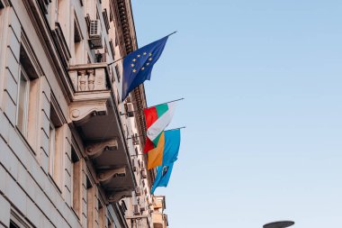 Sofya. Bulgaristan. 09.19.2025. Avrupa Birliği bayrağı, Ukrayna ve Bulgar ulusal bayrağı klasik taş cephe mimarisi ile tarihi balkon binasında sergilendi.