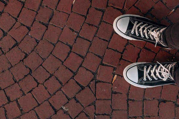 Вид сверху на двух черных каноэ с белыми ленточками на красной брусчатке, демонстрирующих городской уличный дизайн, образ жизни путешественников, обувь для прогулок и расположение камня, формирующее декоративный узор.