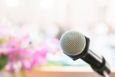 Mikrofonun arka planında hafif bulanık bir konferans odası var.