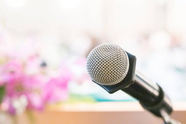 Mikrofonun arka planında hafif bulanık bir konferans odası var.