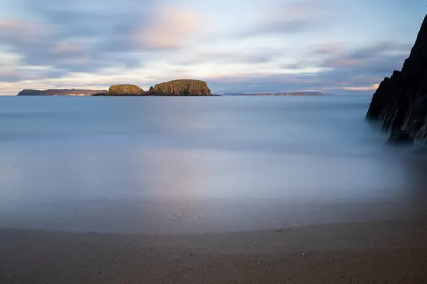 Kuzey İrlanda, Antrim 'deki Ballintoy' un tenha kumsalından çekilen Koyun Adası manzarası güzel, sakin okyanus manzarası ve rüya gibi bulutlar..
