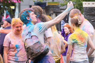 Belfast, Kuzey İrlanda - 17 Ağustos 2024: Geleneksel Mela Karnaval Geçidi, genç erkek ve kadınlardan oluşan bir grup canlı, parlak ve çok renkli Holi tozu.