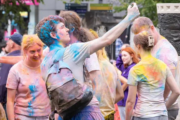 Belfast, Kuzey İrlanda - 17 Ağustos 2024: Geleneksel Mela Karnaval Geçidi, genç erkek ve kadınlardan oluşan bir grup canlı, parlak ve çok renkli Holi tozu.