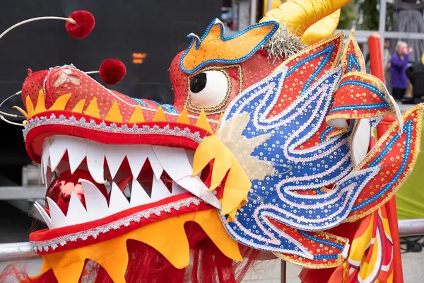 Belfast, Kuzey İrlanda - 17 Ağustos 2024: Geleneksel Belfast Mela Karnaval Geçidi, Çin dans eden kırmızı ve turuncu renkli ejderhanın başını yakın plan.