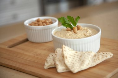 Beyaz kasede bir kase nohut ve Pita ekmeği dilimli humus.