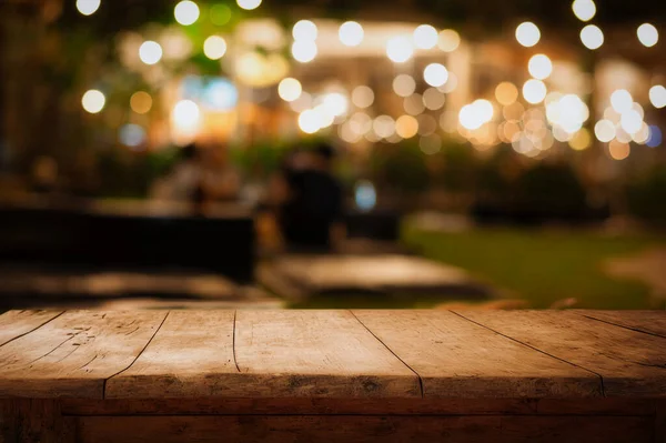漆黑的夜色背景下空旷的木桌顶部和模糊的咖啡店 — 图库照片