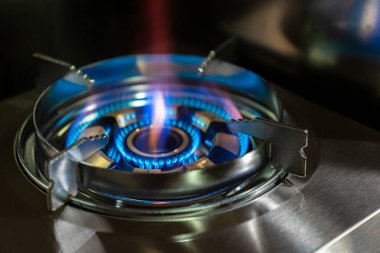 Yakın çekim bir gaz ocağının parlak mavi alevini vurguluyor.