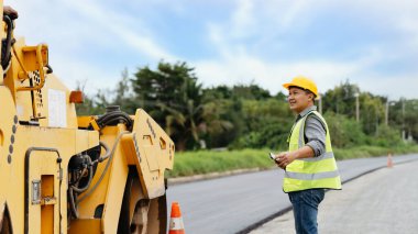 İnşaat alanında ağır ekipmanları denetleyen bir işçi.
