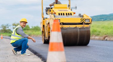Paten makinesi ve trafik konisi olan yol yapım işçisi