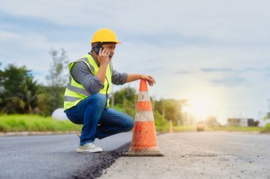 İnşaat işçisi yol çalışmalarını telefonla kontrol ediyor.