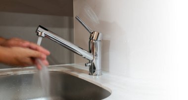 Çağdaş krom musluğun altında akan suyla yıkanan eller. Hijyen ve temizliği parlak, parlak bir tasarımla vurguluyor. Sağlık ve el yıkama alışkanlıklarını desteklemek için ideal..