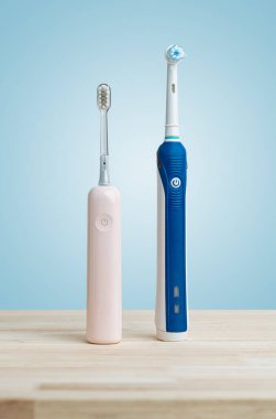 Modern elektrikli diş fırçaları ahşap masada pastel mavisi arka planda hijyen ve diş sağlığı teması için mükemmel