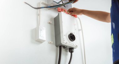 Elektrikçi bir adam ev şarjı kuruyor, özel eve elektrikli araba şarj istasyonu kuruyor.