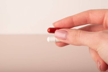 Kadın kapsülleri pembe arka planda tutuyor. Hapları tutan parmaklar, yakın plan. Sağlık, beslenme takviyeleri, vitaminler, depresyon ve hastalıkların tedavisi kavramı. Yüksek kalite fotoğraf