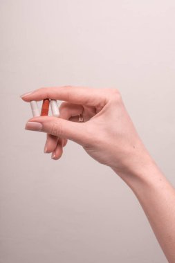 Kadın kapsülleri pembe arka planda tutuyor. Hapları tutan parmaklar, yakın plan. Sağlık, beslenme takviyeleri, vitaminler, depresyon ve hastalıkların tedavisi kavramı. Yüksek kalite fotoğraf