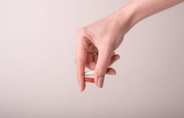 Kadın kapsülleri pembe arka planda tutuyor. Hapları tutan iki parmak, yakın plan. Sağlık, beslenme takviyeleri, vitaminler, depresyon ve hastalıkların tedavisi kavramı. Yüksek kalite fotoğraf