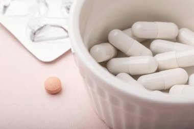 Pembe arka plandaki haplar. Yakın plan. Beyaz kapsüller, pembe haplar, boş haplar. Alerji hapı, antibiyotik, takviye. Tıp, sağlık hizmeti konsepti. Virüs (virüs), grip hastalıkları. Yüksek kalite fotoğraf