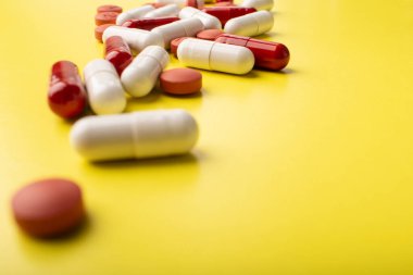 Haplar yakın çekim. Tıbbi haplar ve kapsüller. Sarı arka planda izole edilmiş. Vitaminler, takviyeler, antibiyotikler, alerji hapları. Tıp, sağlık hizmeti konsepti. Virüs ve grip hastalıkları. Yüksek kalite fotoğraf