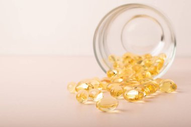 Omega 3 balık yağı pembe arka plandaki bardaktan akıyor. Vitaminler yumuşak kapsüller, morina yağı yakın çekim. Sağlık sigortası, takviye malzemeler, D vitamini. Kopya alanı, afiş. Yüksek kalite fotoğraf