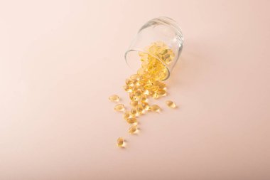 Vitaminler ya da omega 3 balık yağı pembe arka plandaki bardaktan dökülür. Morina yağı kapanışı. Sağlık, takviye, D vitamini ve tedavi kavramı. Uzayı kopyala, afiş. Yüksek kalite fotoğraf