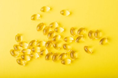 Omega 3 balık yağı sosisi. Sarı arka planda yumuşak kapsüllerdeki vitaminler, morina yağı. Sağlık, takviye, D vitamini ve tedavi kavramı. Uzayı kopyala, düz çizgi, pankart. Yüksek kalite fotoğraf