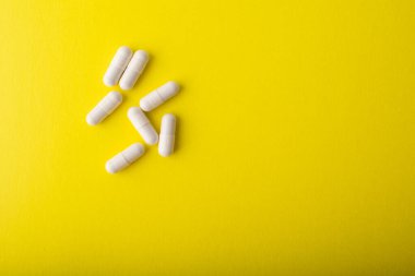 Sarı arka planda beyaz haplar. C vitamini takviye kapsülleri. Beyaz vitamin kapsülü. Grip, grip ve virüsün tedavisi ve önlenmesi. Sağlık hizmeti konsepti afişi. Yüksek kalite fotoğraf