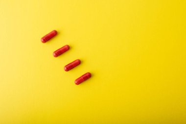 Sarı arka planda kırmızı haplar var. Vitaminler, destek kapsülleri. Tedavi depresyonu, hastalıklar, grip, nezle, virüs. Sağlık hizmeti konsepti afişi. Yüksek kalite fotoğraf