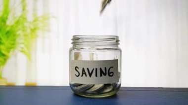 Bozukluklar, birikim, yatırım stratejileri ve uzun vadeli gelir ve emeklilik güvencesini simgeleyen bir tasarruf etiketi ile cam bir kavanoza düşüyor. Resmetmek için ideal