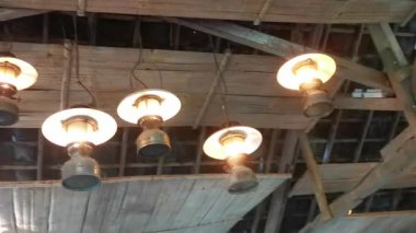 Ahşap kiriş tavandan sarkan dekoratif vintage fenerlerle kırsal bir iç mekanın sıcak atmosferini yakalayın. Eski tarz ve doğal dokular rahat bir atmosfer yaratır.