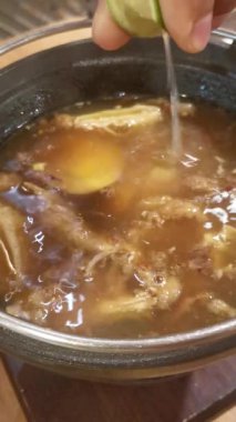 Bir çömlekte buharı tüten sıcak yağmurun bir porsiyonu tavuk, haşlanmış yumurta ve fasulye filizi içerir. Ekstra lezzetli bir tat için biraz limon ekle..