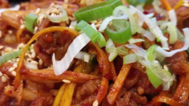 Baharatlı Kore Pork Bulgogi 'nin baştan çıkarıcı yakın çekimini keşfedin, canlı yeşil soğanlar ve susam tohumlarıyla tamamlanan cızırtılı tatlar sunarak, bir mutfak başyapıtı yaratın..