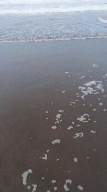 Kumlu bir kumsalda okyanus dalgalarının zarif bir şekilde çarpışını gösteren sakinleştirici bir video. Bu deniz manzarası, akan suyun hareketini ve doğanın dingin güzelliğini gözler önüne seren sakin bir kaçış sağlar..