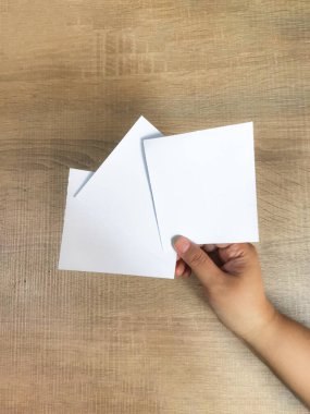 Ahşap bir arka planda bir yığın temiz, beyaz kağıt sergiliyor. Bir mesaj ya da fikir için hazır. Minimalist kompozisyon gösterme potansiyeli veya yeni projeler