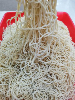 Bu fotoğraf, onların hassas dokusunu ve basitliğini vurgulayan, aşçılık hazırlığının görsel bir temsilini ve Asyalı özünü gözler önüne seren, taşmış bir sade şehriye yığınını gösteriyor.