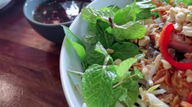 A visually rich video showcasing a vibrant Vietnamese noodle bowl, highlighting the fresh herbs, crispy spring rolls, and intricate textures. Emphasizing healthy eating, perfect for culinary content