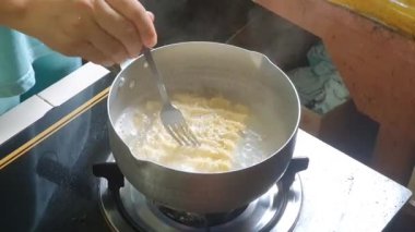 POV elleri evde hazır şehriye çorbası pişiriyor. Asyalı kadın eli evdeki kaynar suya kuru erişte koyup karıştırıyor. Gaz sobasında buharlı yemek..