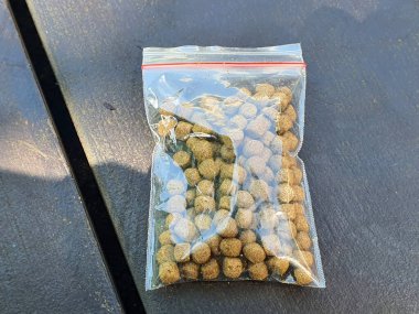 Havuz kenarındaki güvertede koi topakları. Koi yemek tabletleri. Göl kenarındaki güvertede koi havuzu topakları