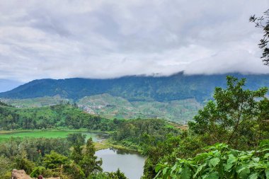 Dieng 'deki Serene Telaga Warna Gölleri, Central Java ve Lush Green Dağları: Huzurlu Suların Nefes Kesen Manzarası, Rolling Hills ve Bulutlu Gökyüzü Altındaki Verdant Ormanları, Doğanın Güzelliği