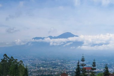Majestic Mountain Views: Şehir ve Doğa 'nın Panoramik Manzarası, Yüksek Bakış Açısı, Serene Bulutları ve Yeşillik Gösteriyor. Dağların Arasında Yuvalanmış Bir Şehir