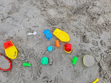 Sandy Plajı 'na Renkli Plastik Oyuncaklar Saçıldı: Bir Yaz Gününün Neşeli Sahnesi, Çocukluk Eğlencesinin Eğlencesini Yakalıyor. Geride bırakılan plaj oyuncakları, tamamlanmamış kumdan kaleler, kumdan oyunlar maceraları.