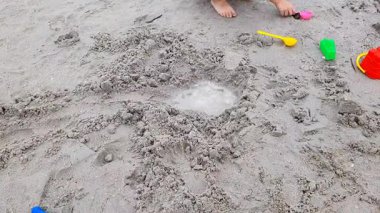 Kumsalda kumla oynayan çocuklar, bir kale, göl ve su kanalı inşa ediyorlar..