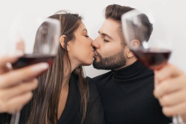 Evli çiftler şarap içerken öpüşürler.