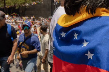 Arka planda insanların seçim hırsızlığını protesto ettiği Venezuela bayrağı