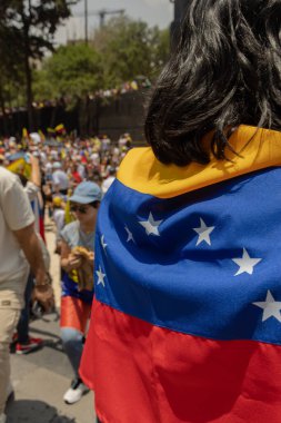 Arka planda insanların seçim hırsızlığını protesto ettiği Venezuela bayrağı