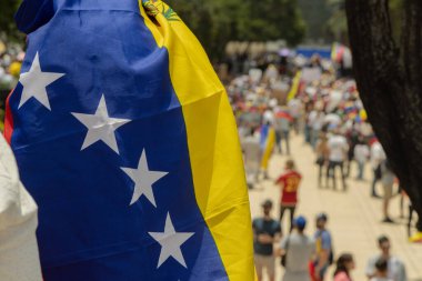 Arka planda insanların seçim hırsızlığını protesto ettiği Venezuela bayrağı