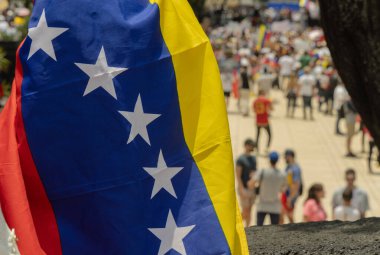 Arka planda insanların seçim hırsızlığını protesto ettiği Venezuela bayrağı