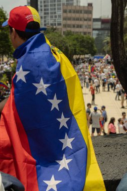 Venezuelan flag with people in the background protesting against the theft of the elections clipart