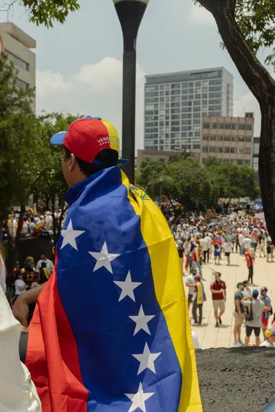 stock image Venezuelan flag with people in the background protesting against the theft of the elections