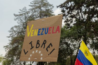 Arka planda Özgür Venezuela yazan protesto pankartı