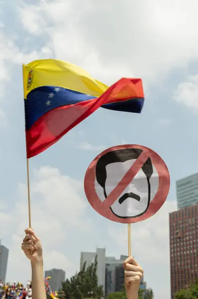 Venezuela bayrağı havada sallanırken Maduro 'ya karşı protesto afişi